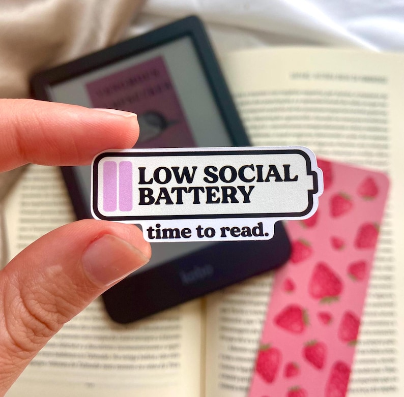 Pu&ograve; includere: Adesivo bianco con un'icona di batteria rosa e il testo "LOW SOCIAL BATTERY time to read."