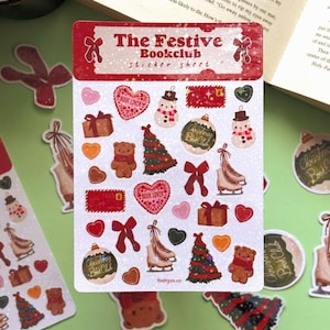 以下が含まれることがあります： 「The Festive Bookclub」と題されたステッカーシート。雪だるま、クリスマスツリー、ハート、リボン、ギフトボックス、スケート靴、テディベアなどのクリスマスをテーマにしたステッカー。ステッカーは赤、緑、茶色、白です。