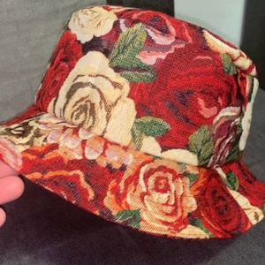May include: A red and white floral bucket hat with a large rose pattern.