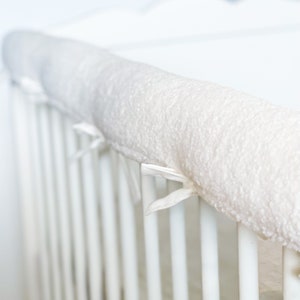Przytulny i ochronny pokrowiec na szczebelki łóżeczka, wykonany z białego materiału Teddy - zawiera miękkie wypełnienie - idealny dla bezpieczeństwa i wygody Twojego dziecka!