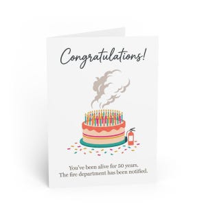 Peut inclure: Une carte de vœux blanche avec le texte Congratulations! au-dessus d'un gâteau à étages avec de nombreuses bougies allumées et un panache de fumée. Un extincteur rouge est placé à côté du gâteau. Le texte en bas indique You've been alive for 50 years.