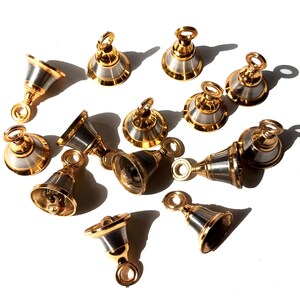 Op de afbeelding: Een verzameling van 12 kleine zilveren en gouden bellen met een decoratief ontwerp. De bellen zijn willekeurig gerangschikt op een wit oppervlak.
