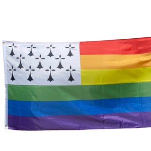 Peut inclure: Un drapeau blanc avec des hermines noires, représentant la Bretagne, est combiné avec un drapeau arc-en-ciel de la fierté. Le drapeau est en tissu et a une apparence légèrement ondulée.