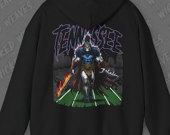 May include: Black hoodie featuring a graphic of a warrior with a flaming sword and the word "Tennessee" in a stylized font. The design includes a cityscape background and the artist's signature. The hoodie has a hood and long sleeves.