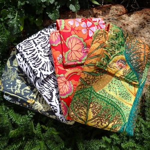 May include: A selection of patterned fabric clutches in a variety of colours. The designs include floral, zebra print, and leaf patterns. The clutches are folded and stacked, with colours such as red, green, and black.