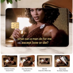 K&ouml;nnte beinhalten: Eine individuelle Karte mit einer Frau, die ein Weinglas h&auml;lt, mit dem Text "what can a man do for me except bow or die?". Die Karte hat einen goldenen Chip und wird mit anderen Karten und einer Brieftasche gezeigt.