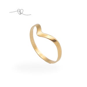 May include: A gold-colored ring with a V-shaped design. The ring is made of a shiny metal and has a smooth surface. The ring is shown on a white background. A small line drawing of a heart is in the upper left corner.
