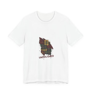 May include: White t-shirt featuring a distressed plaid design in shades of red, green, and gold. The word "UNPOLISHED" is printed in a dark red font below the plaid graphic. The shirt has a classic crew neck.
