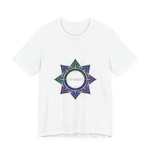 May include: White t-shirt featuring a geometric design with green, purple, and blue accents. The design includes a central circle with the text "STAY RADIANT" and is surrounded by a starburst pattern.