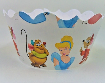 May include: White cupcake liners with a Cinderella theme. The liners feature Cinderella, Gus, and Jaq. The liners are decorated with blue, pink, and yellow colors.