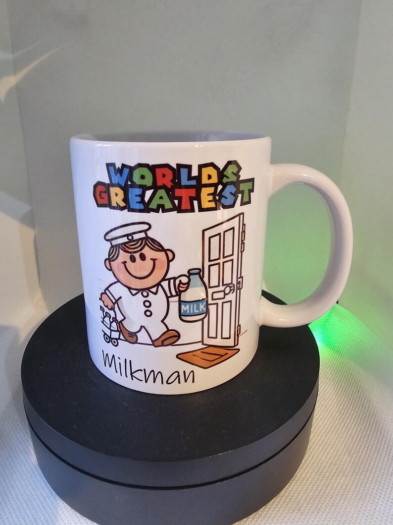 May include: White ceramic mug with a cartoon illustration of a milkman delivering milk. The mug has the text "WORLD'S GREATEST" in colorful letters and "Milkman" at the bottom.
