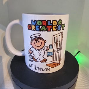 May include: White ceramic mug with a cartoon milkman delivering milk. The mug has the text "World's Greatest Milkman" printed on it.