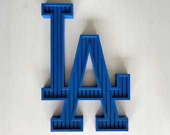 Può includere: Un logo LA 3D blu con un design a righe. Il logo è in plastica ed è una decorazione popolare per i fan dei Los Angeles Dodgers.