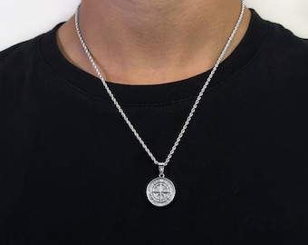May include: A silver rope chain necklace with a silver pendant featuring a circular design with intricate details.
