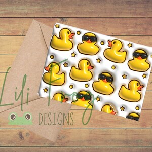 May include: A greeting card featuring a pattern of yellow rubber ducks wearing sunglasses, stars, and circles. A brown envelope is next to the card. The text "Lili Designs" is visible on the envelope.