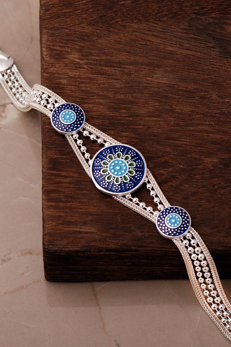 A handcrafted 925 sterling silver woven mesh bracelet featuring a round central plate with the intricate Sun of Mardin motif filled with colorful enamel.