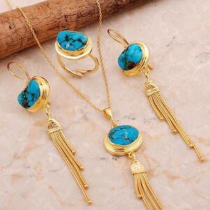 A handmade 925 sterling silver gold plated jewelry set featuring a woven tassel pendant necklace, dangling earrings, and an adjustable ring, all adorned with natural blue turquoise stones.