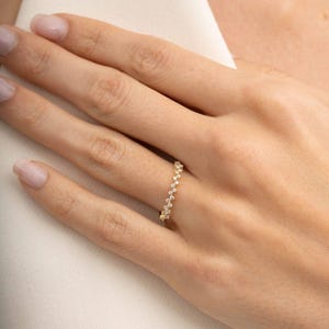 A thin 3mm wide silver ring coated in green gold plating with sparkling clear cubic zirconia stones set around the band.