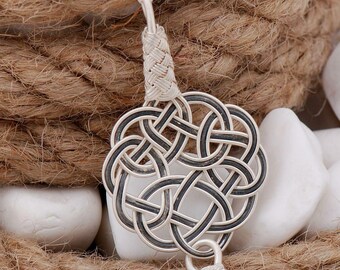 May include: A silver necklace with a detailed, intricate knot pendant. The pendant is made of woven silver wire and has a small, round silver bead at the bottom.