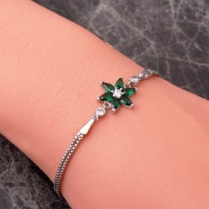 A delicate 925 sterling silver bracelet featuring a centrally placed lotus flower motif set with a brilliant gemstone, attached to a fine chain with an extension link.