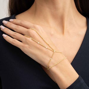 A delicate double-wrap gold-plated 925 sterling silver Sahmeran hand chain with hand-engraved curb chain detailing that sparkles like gemstones.