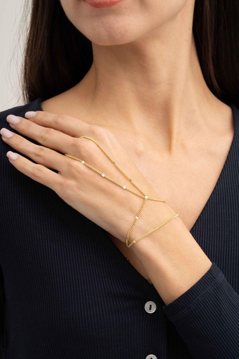 A delicate double-wrap gold-plated 925 sterling silver Sahmeran hand chain with hand-engraved curb chain detailing that sparkles like gemstones.