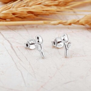 A pair of small silver earrings featuring a minimalist tulip shape adorned with sparkling white zircon stones, rhodium‑plated for a bright finish.
