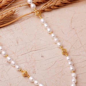 A elegant handmade white pearl strand necklace decorated with gold-plated 925 sterling silver filigree spacers and finished with an adjustable extension chain.