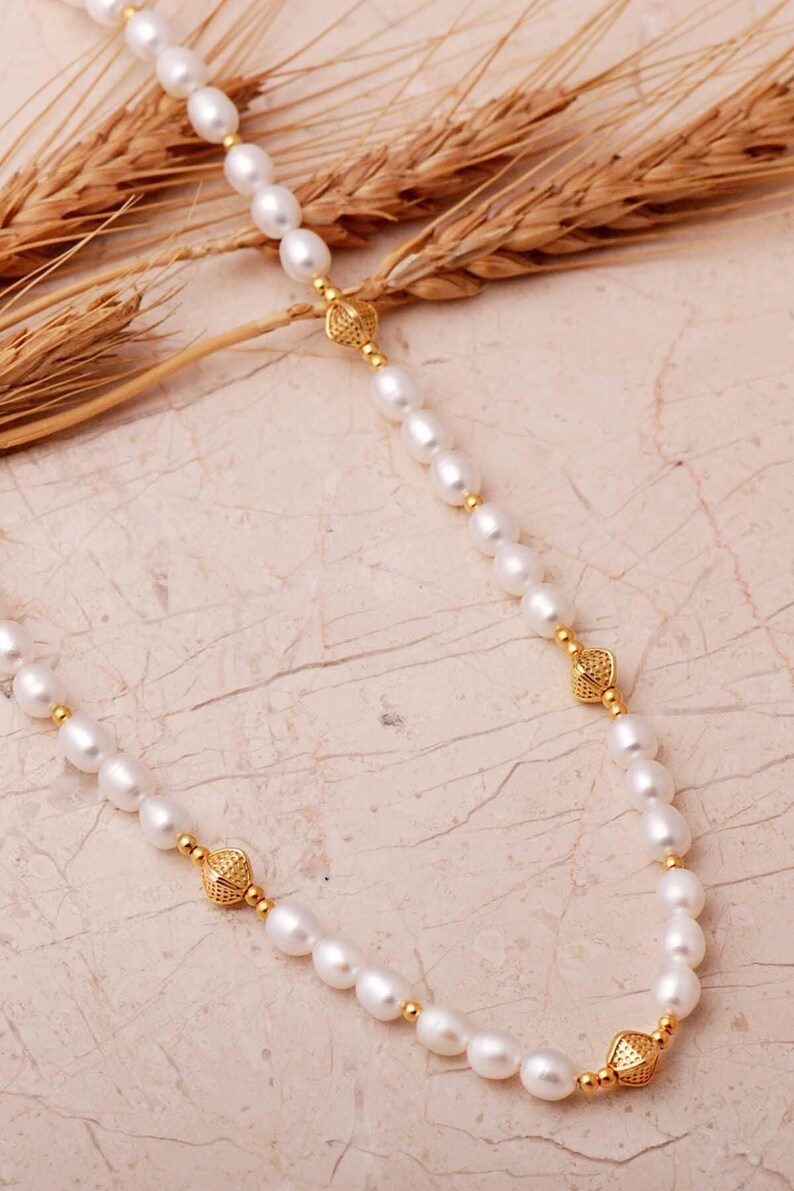 A elegant handmade white pearl strand necklace decorated with gold-plated 925 sterling silver filigree spacers and finished with an adjustable extension chain.