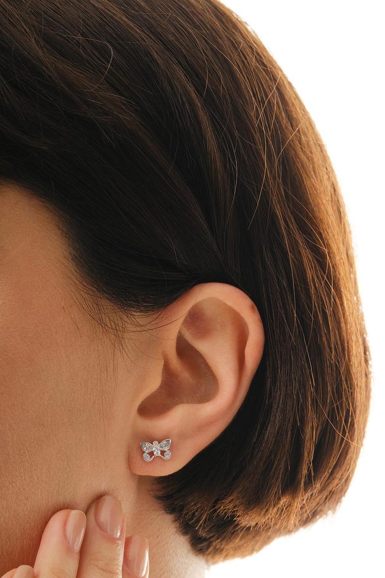 Mini butterfly earrings made of rhodium‑plated sterling silver with a white zircon stone, measuring 6 mm by 9 mm.