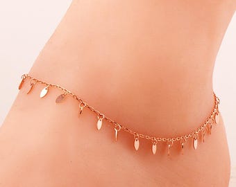 May include: A rose gold anklet featuring a delicate chain adorned with numerous small, flat, oval-shaped metal charms hanging at regular intervals along the entire length of the chain, creating a subtle and uniform dangling effect.