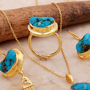 A handmade 925 sterling silver gold plated jewelry set featuring a woven tassel pendant necklace, dangling earrings, and an adjustable ring, all adorned with natural blue turquoise stones.