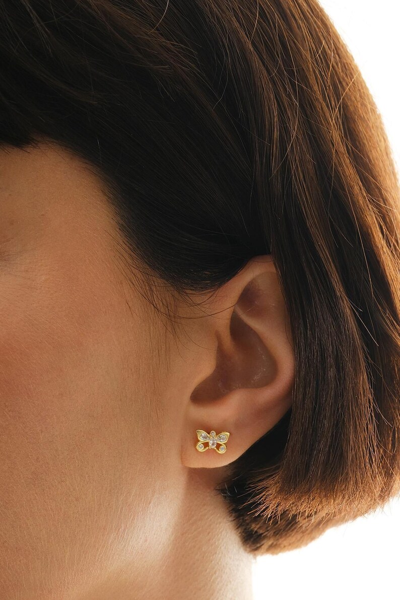 Mini butterfly earrings made of 925 sterling silver with green gold rhodium plating and white zircon stones, measuring 6 mm tall by 9 mm wide.