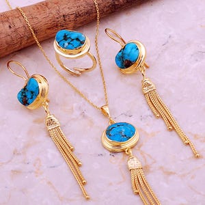 A handmade 925 sterling silver gold plated jewelry set featuring a woven tassel pendant necklace, dangling earrings, and an adjustable ring, all adorned with natural blue turquoise stones.