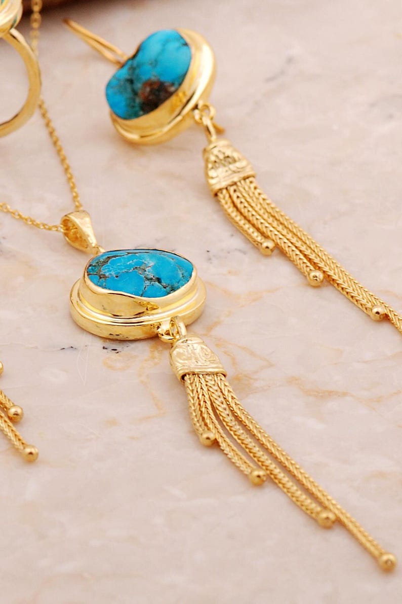 A handmade 925 sterling silver gold plated jewelry set featuring a woven tassel pendant necklace, dangling earrings, and an adjustable ring, all adorned with natural blue turquoise stones.