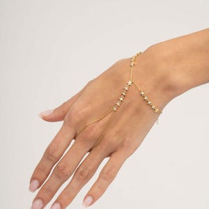 Gold plated 925 sterling silver star hand chain bracelet with sparkling zircon accents connecting from finger to wrist.