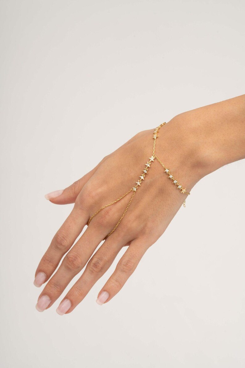 Gold plated 925 sterling silver star hand chain bracelet with sparkling zircon accents connecting from finger to wrist.