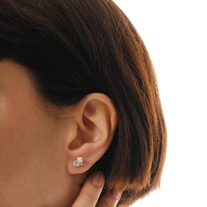 A pair of mini 925 sterling silver stud earrings featuring a detailed seashell and starfish motif accented with a small white pearl and butterfly backs.