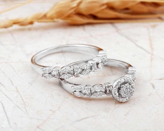 May include: A set of two silver-toned rings featuring marquise-cut stones along the bands. One ring includes a central circular cluster of small round stones, while the other band is adorned with a continuous row of marquise-cut stones.