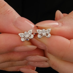 Mini butterfly earrings made of rhodium‑plated sterling silver with a white zircon stone, measuring 6 mm by 9 mm.
