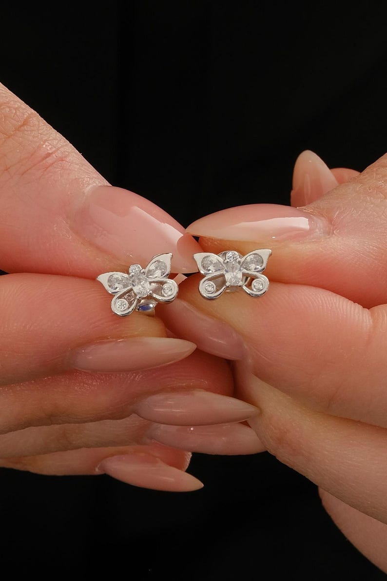 Mini butterfly earrings made of rhodium‑plated sterling silver with a white zircon stone, measuring 6 mm by 9 mm.