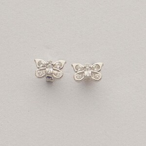 Mini butterfly earrings made of rhodium‑plated sterling silver with a white zircon stone, measuring 6 mm by 9 mm.