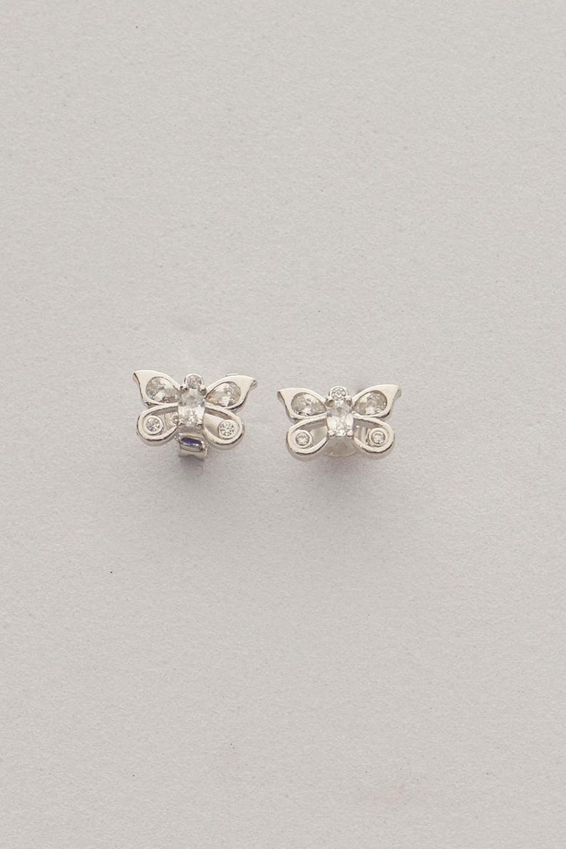 Mini butterfly earrings made of rhodium‑plated sterling silver with a white zircon stone, measuring 6 mm by 9 mm.