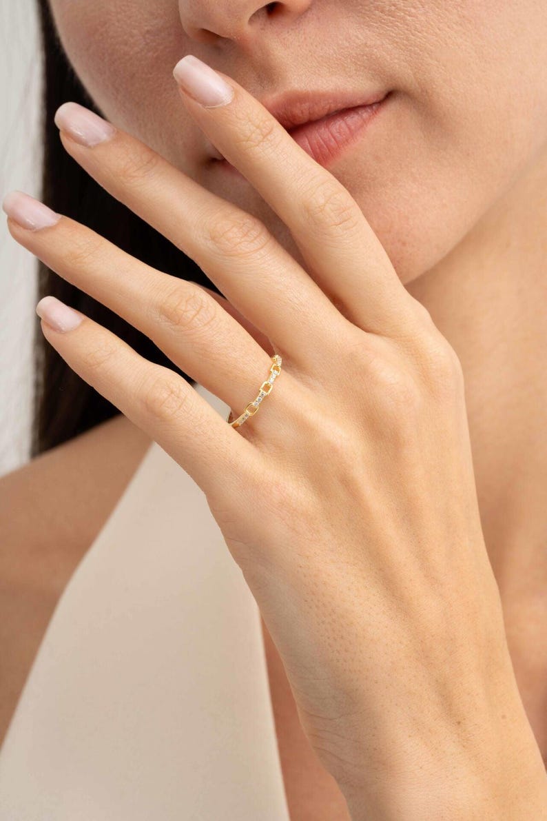 A delicate gold-plated 925 sterling silver chain link band ring encrusted with sparkling clear cubic zirconia stones against a neutral background.