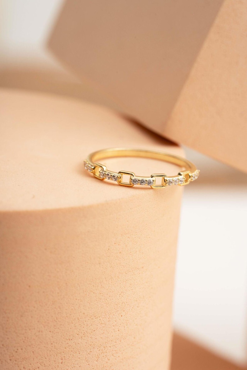 A delicate gold-plated 925 sterling silver chain link band ring encrusted with sparkling clear cubic zirconia stones against a neutral background.