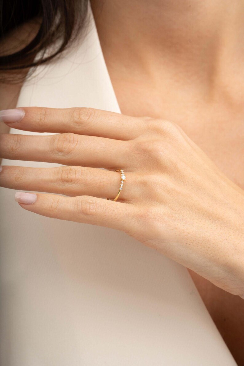 A close‑up of a thin silver ring with green gold plating and sparkling zircon stones, featuring a larger 2.5 mm center stone and smaller 1.5 mm accents.