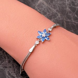 A delicate 925 sterling silver bracelet featuring a centrally placed lotus flower motif set with a brilliant gemstone, attached to a fine chain with an extension link.