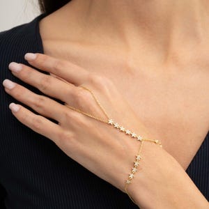 Gold plated 925 sterling silver star hand chain bracelet with sparkling zircon accents connecting from finger to wrist.