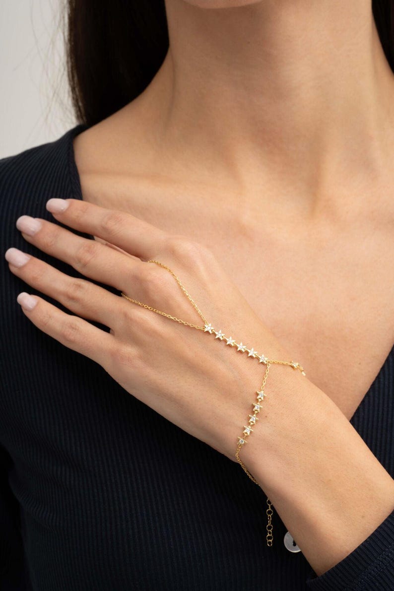 Gold plated 925 sterling silver star hand chain bracelet with sparkling zircon accents connecting from finger to wrist.
