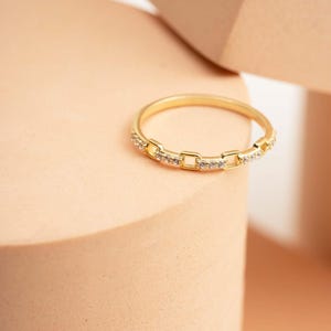 A delicate gold-plated 925 sterling silver chain link band ring encrusted with sparkling clear cubic zirconia stones against a neutral background.